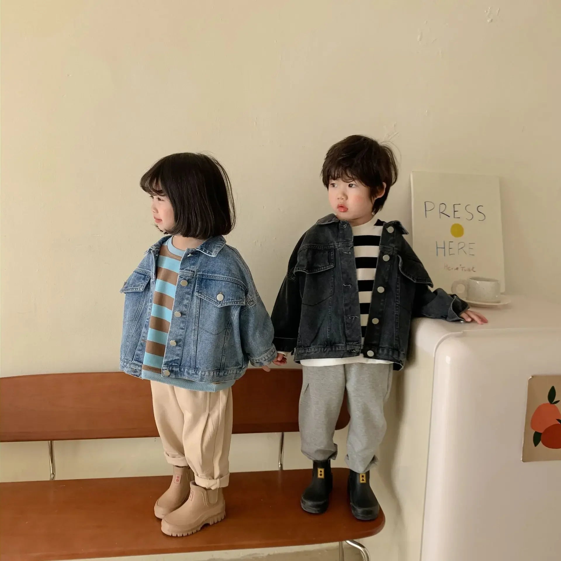 Two toddlers in denim jackets striped tops and boots showcasing trendy kids outfits uae in neutral tones